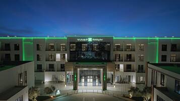 Un hotel Holiday Inn con fachada moderna, señalización iluminada y entrada principal.