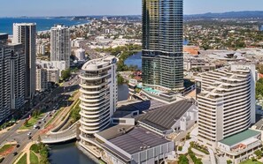 A high-rise hotel with a modern design, featuring a curved facade and a rooftop pool.