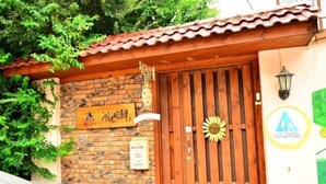 A wooden gate with a sun decoration, a brick wall, and a sign with Chinese characters. - Huxiangyi Internationa Youth Hostel Changsha Yuelushan (Changsha)