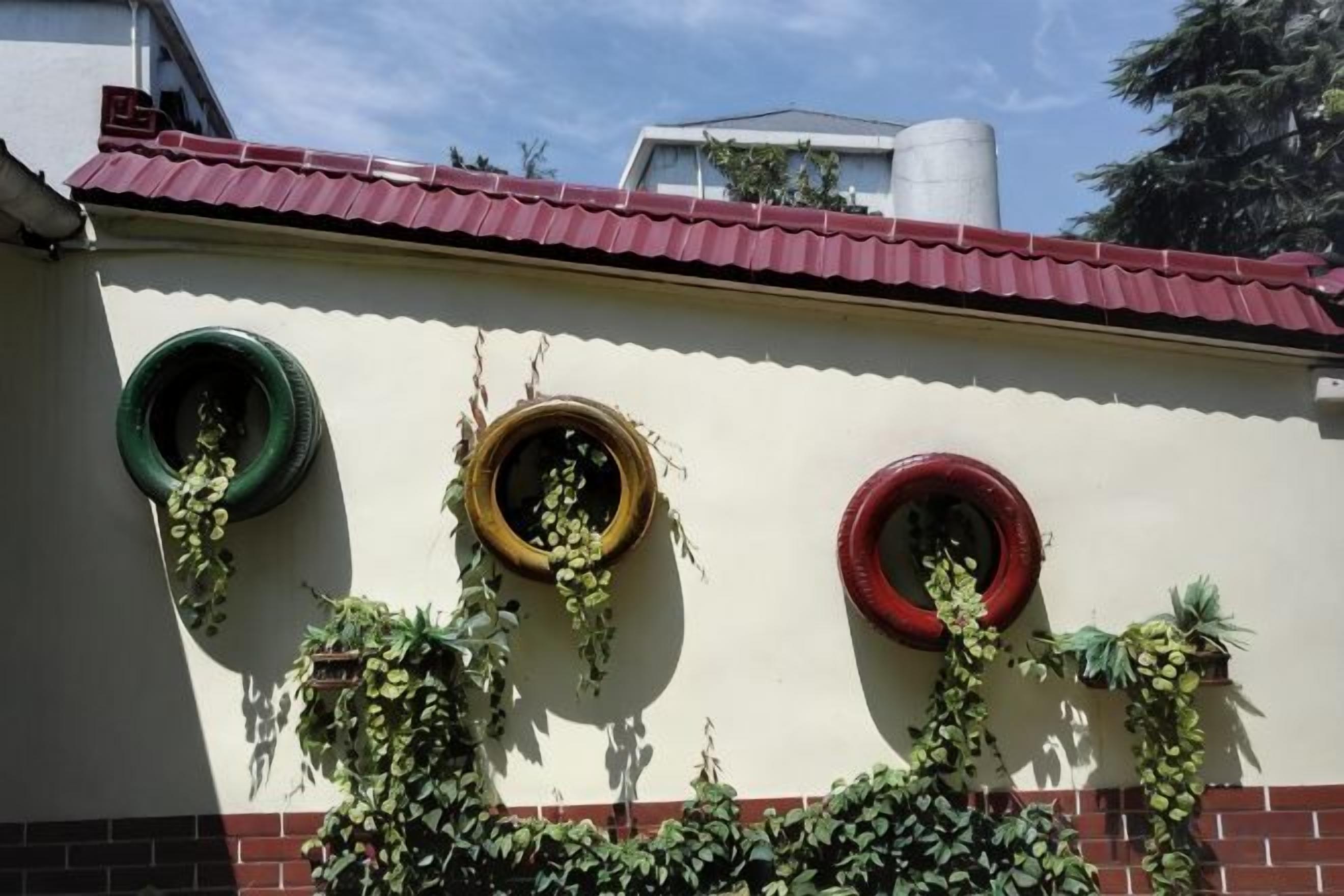 A building with a red roof and three circular windows with plants growing in them.