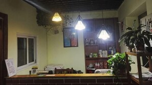 A reception area with a brick counter, hanging plants, and a window. - Huxiangyi Internationa Youth Hostel Changsha Yuelushan (Changsha)