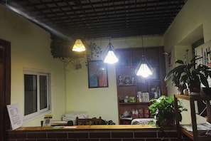 Un espace d’accueil avec un comptoir en briques, des plantes suspendues et une fenêtre.