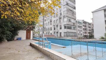 Una piscina con muelle de madera y escalera de metal, rodeada por un edificio con varios balcones.