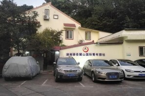 A building with a sign indicating it is a car rental service. There are several cars parked in front, and a covered car is also visible. - Huxiangyi Internationa Youth Hostel Changsha Yuelushan (Changsha)