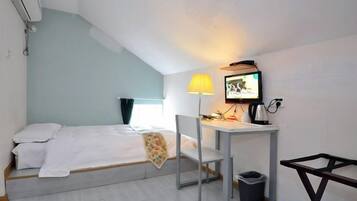 Habitación pequeña con una cama individual, escritorio, silla y televisor.