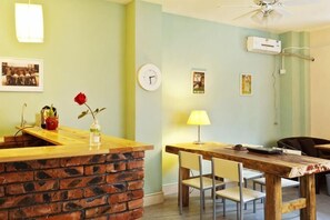 Una habitación con mostrador de ladrillo, una mesa de comedor con sillas, un reloj y aire acondicionado instalado en la pared.