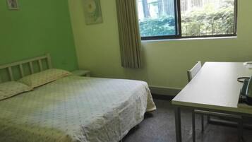 Una habitación con cama, una mesa y un ventanal.