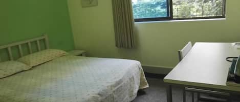 A room with a bed, a table, and a window.