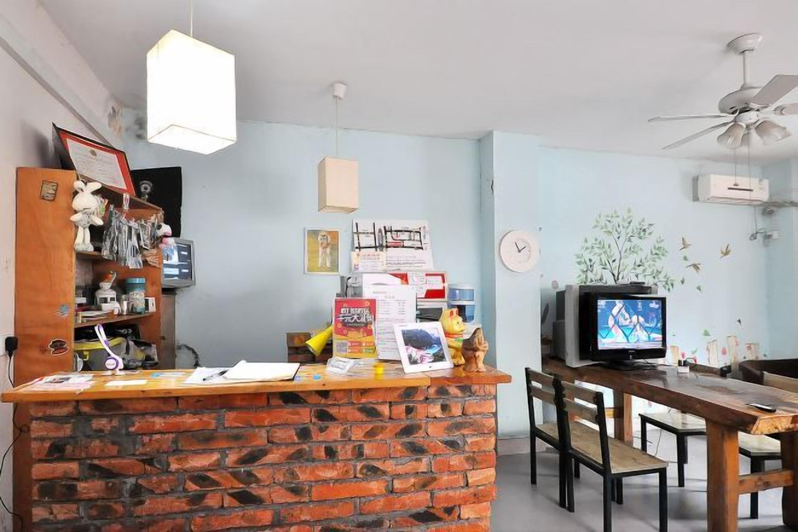 A reception area with a brick counter, a television, and a dining area with wooden furniture.