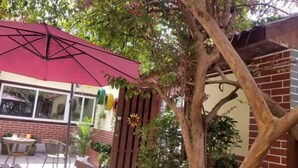 An outdoor seating area with a red umbrella, wooden benches, and potted plants. - Huxiangyi Internationa Youth Hostel Changsha Yuelushan (Changsha)