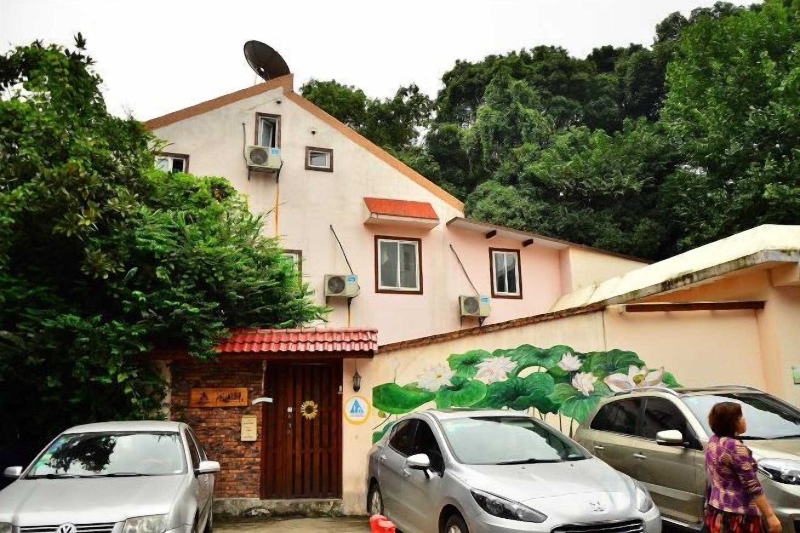 Un edificio con antena parabólica, unidades de aire acondicionado, una puerta con letrero y un mural en la pared.