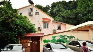 Un edificio con antena parabólica, unidades de aire acondicionado, una puerta con letrero y un mural en la pared.