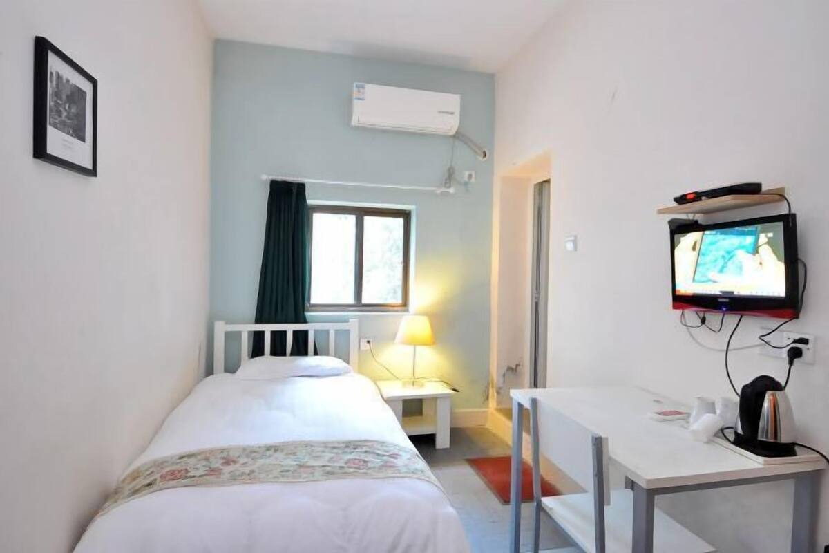Une chambre à coucher comprenant un lit, un bureau, un téléviseur et un appareil de climatisation.