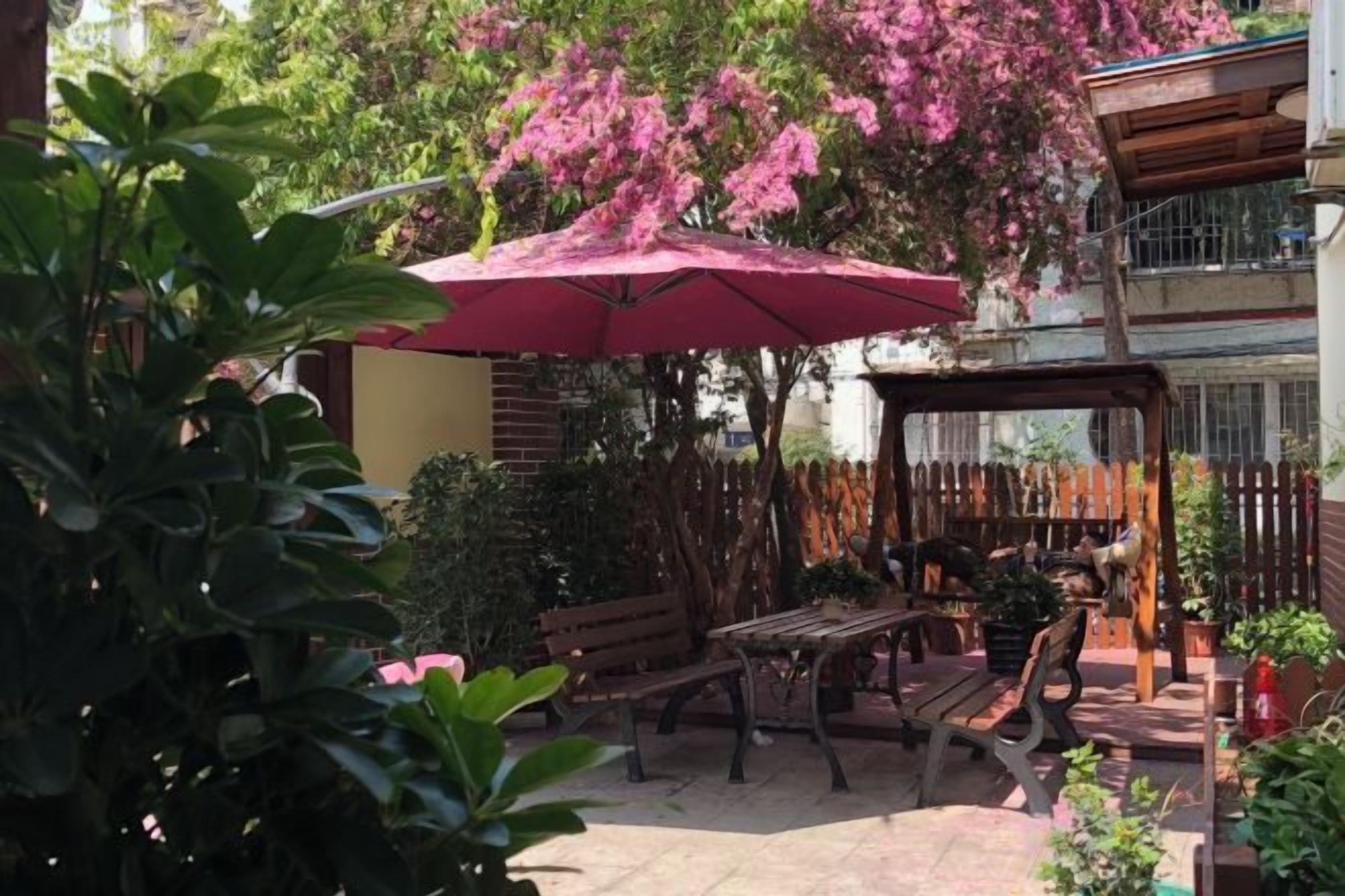 An outdoor patio with a wooden table, benches, and a large umbrella.
