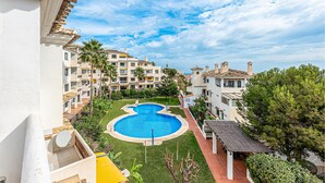 Un resort con piscina central, varios balcones y abundante vegetación.