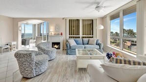 Un salón amplio con chimenea, un balcón con vistas y un gran ventanal.