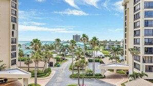 Un resort con edificios de varios pisos, palmeras, cielo despejado y vista al océano.