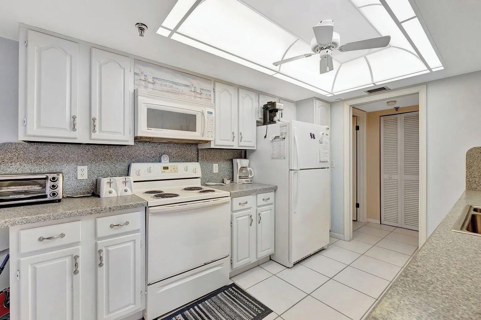 A modern kitchen with white cabinets, a microwave, a stove, and a refrigerator.