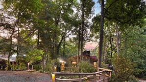 A wooden deck leading to a stone building surrounded by trees. - High-Speed WiFi, Pool Table, private HOT TUB, Fire Pit, Game Room, 2 Kitchens! (Maggie Valley)