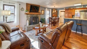 A cozy living room with a fireplace, leather sofa, and a dining area. - High-Speed WiFi, Pool Table, private HOT TUB, Fire Pit, Game Room, 2 Kitchens! (Maggie Valley)
