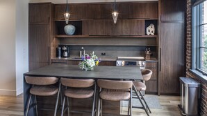 A modern kitchen with a large island, wooden beams, and pendant lighting. - Elevation Lofts Hotel (Asheville)