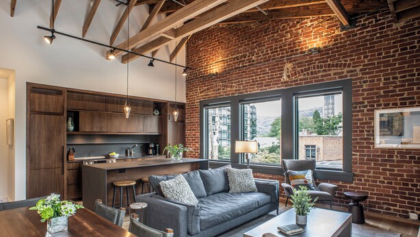 A modern kitchen with dark wood cabinets, a central island, and pendant lighting. - Elevation Lofts Hotel (Asheville)