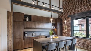 A modern kitchen with a central island, bar stools, and pendant lighting. - Elevation Lofts Hotel (Asheville)