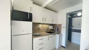 Uma cozinha compacta com armários brancos, micro-ondas, pia e lava-louças.