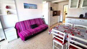 Um espaço de estar compacto com sofá, mesa de jantar e cozinha compacta.