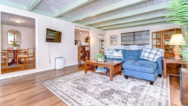 A spacious living room with a blue sofa, wooden coffee table, and a patterned rug.