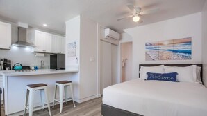 Una habitació d'hotel moderna amb un llit gran, una cuineta petita i vista a la platja.