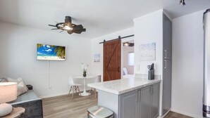 A modern kitchen with grey cabinets, a marble countertop, and a ceiling fan.