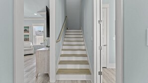Una escalera con paredes blancas y escalones de madera que conduce a una plataforma.