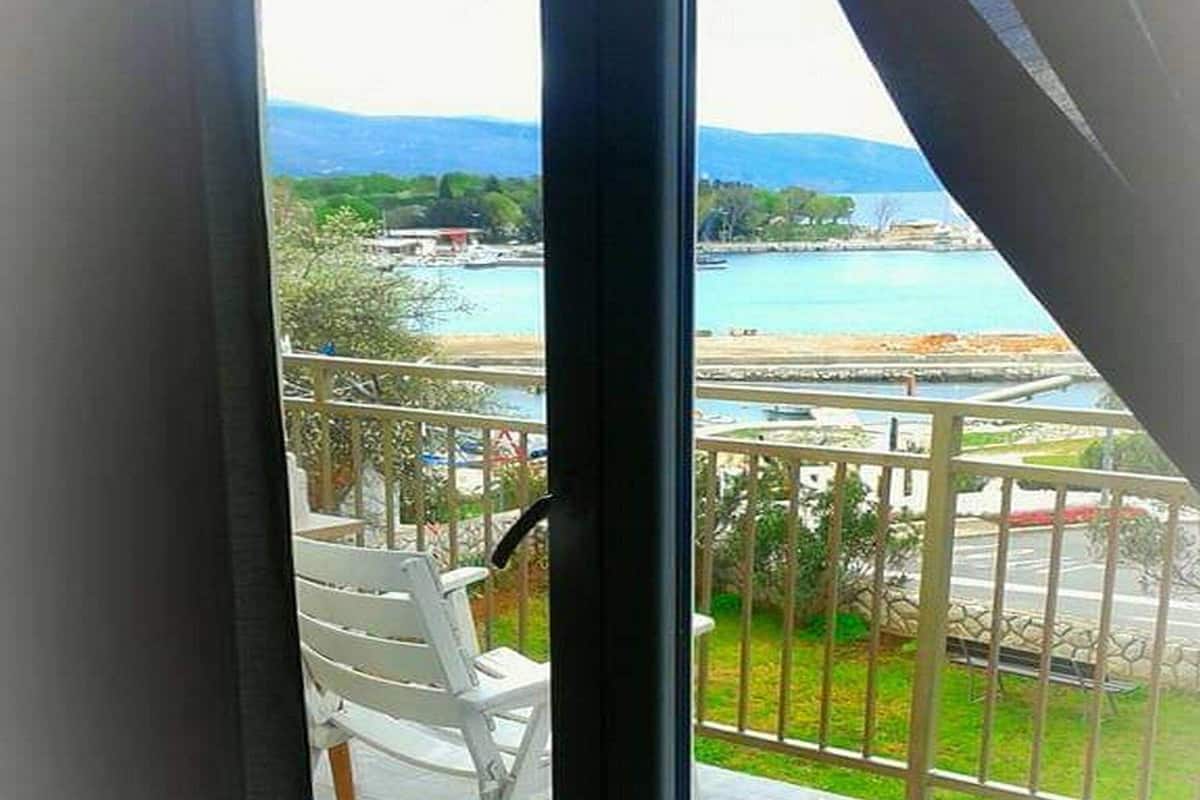 Un balcon offrant une vue sur une zone côtière, comprenant une étendue d’eau et des montagnes au loin.