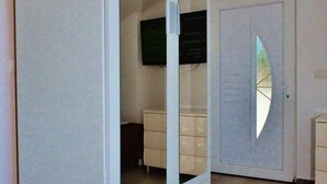 A room with a large white wardrobe, a small white dresser, and a wall-mounted TV. - Apartments Brzica (Novi Vinodolski)