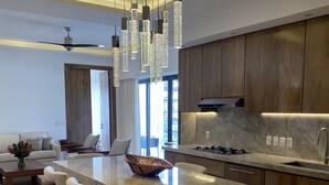Een moderne keuken met een groot kookeiland, houten kasten en hangende lampen.