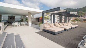 Een moderne terrasruimte buiten met een pooltafel, zitplaatsen en een pergola.