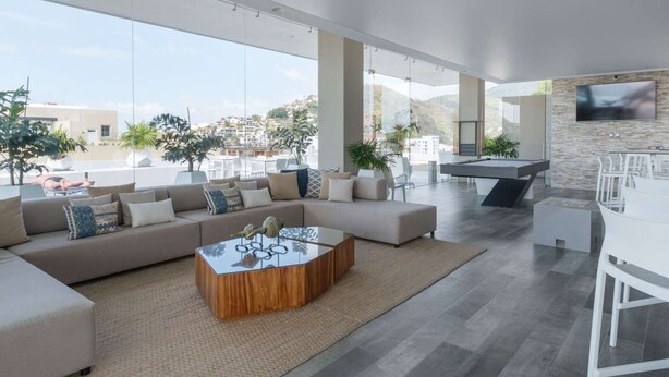 Een moderne woonkamer met een grote hoekbank, een glazen salontafel en een eetgedeelte met witte meubels.