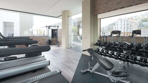 Een sportschool met loopbanden, een bankdrukrek en gewichten.