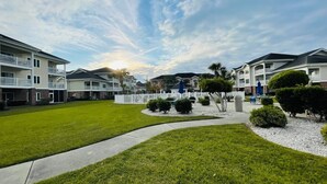 A residential area with multiple two-story houses, a well-maintained lawn, and a white picket fence. - First floor gorgeous condo in Myrtle Beach (Myrtle Beach)
