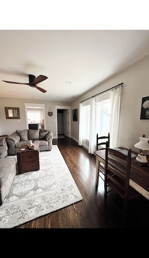 Relax in this spacious living area with a high ceiling, ceiling fan, and comfortable dining space.