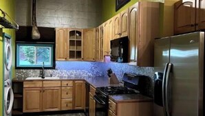 Una cocina compacta con armarios de madera, un refrigerador de acero inoxidable y un horno empotrado.