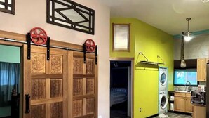 Un espacio habitable compacto con comedor, cocina equipada con lavadora y dormitorio con cama.