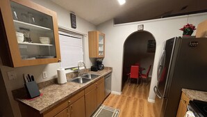 A compact kitchen with wooden cabinets, a stainless steel sink, and a refrigerator. - Blissful Guest House  (Ocoee)
