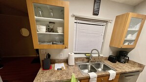 A compact kitchen with wooden cabinets, a double sink, and a coffee maker. - Blissful Guest House  (Ocoee)