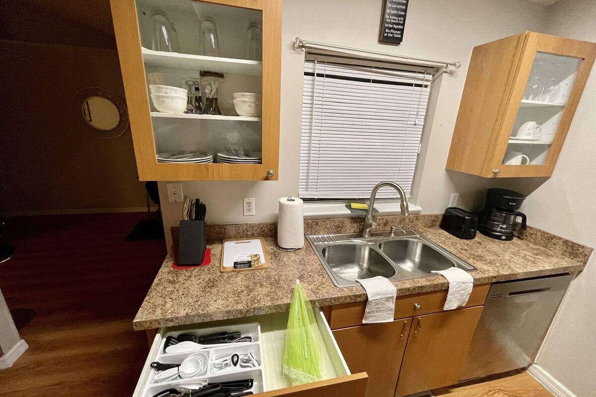 A compact kitchen with wooden cabinets, a double sink, and a coffee maker.