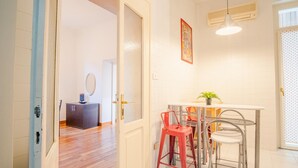 Una cucina moderna con un piano di lavoro bianco, sgabelli da bar rossi e una lampada a sospensione.