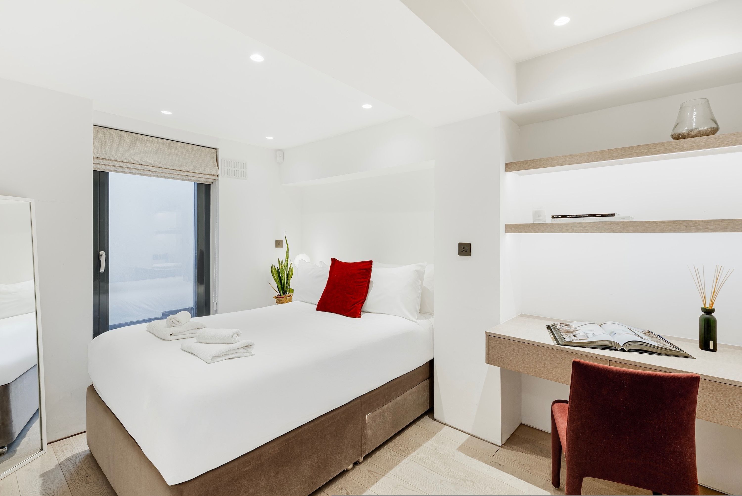 A modern hotel room with a large bed, a desk, and a window.