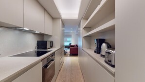 A narrow kitchen with a microwave, coffee maker, and toaster on the countertops.