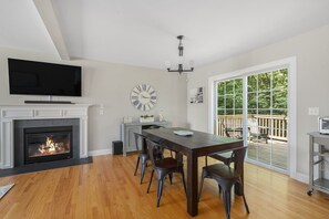 A dining area with a fireplace, a clock, and a view of the outdoors. - 3BR Near Beaches w/ Fire Pit & Large Yard (Narragansett)